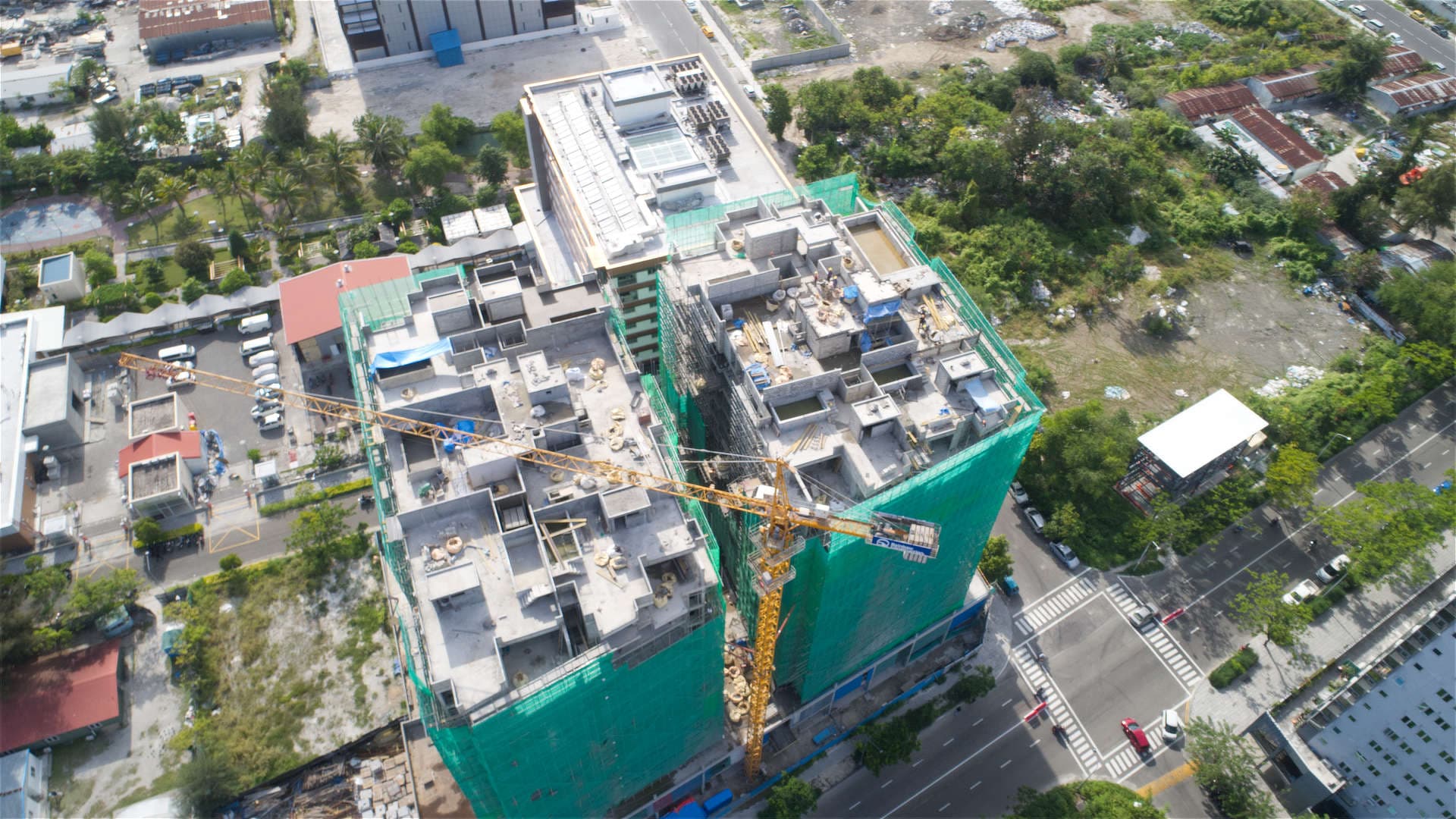 Aerial photograph of Rainbow Construction's yard: cranes, excavators, transit mixers, tipper trucks and stacked materials laid out on sand.