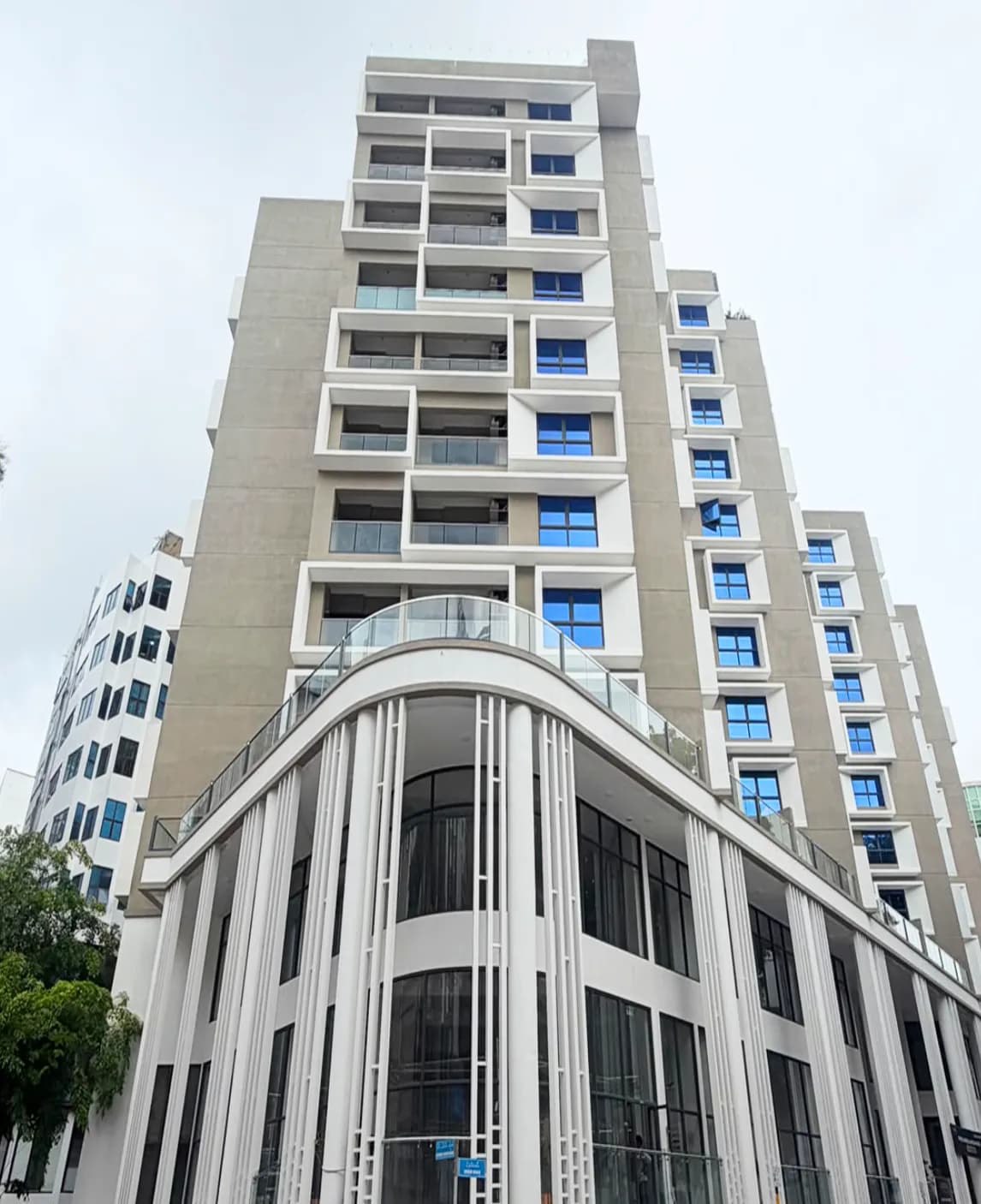 Photograph of Luxera, a residential tower on Sosun Magu, Malé, with a curved white podium and blue-glazed balconies.